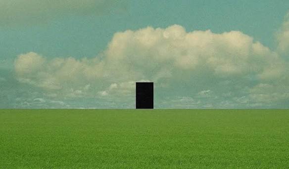 Monolito negro rectangular de pie en mitad de un campo verde