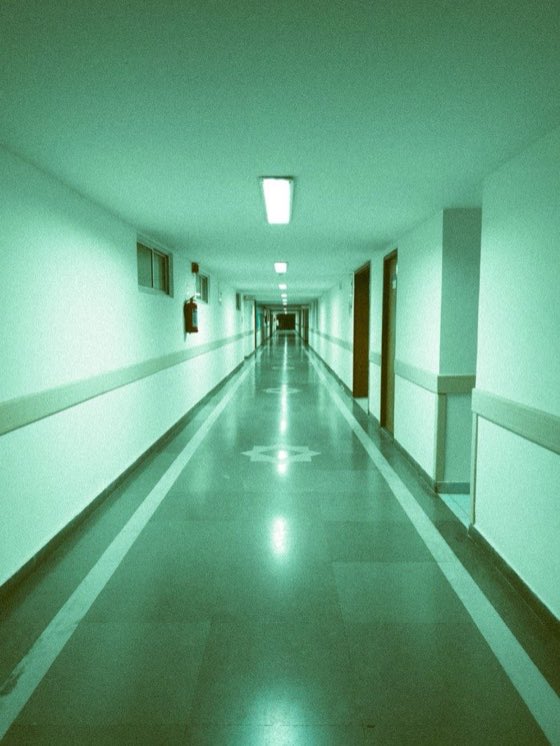 Pasillo institucional vacío con luz verdosa de fluorescente